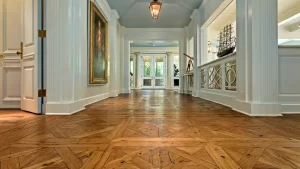 Reclaimed oak wide plank flooring in a custom parquet pattern with nail holes and stress cracks in a grand white foyer.