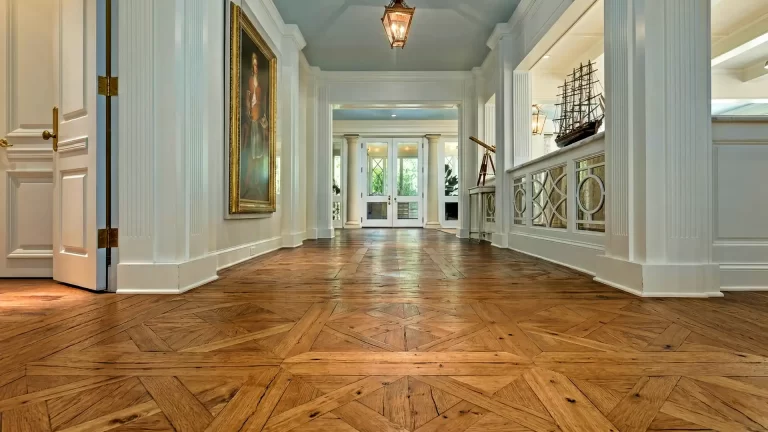 Reclaimed oak wide plank flooring in a custom parquet pattern with nail holes and stress cracks in a grand white foyer.