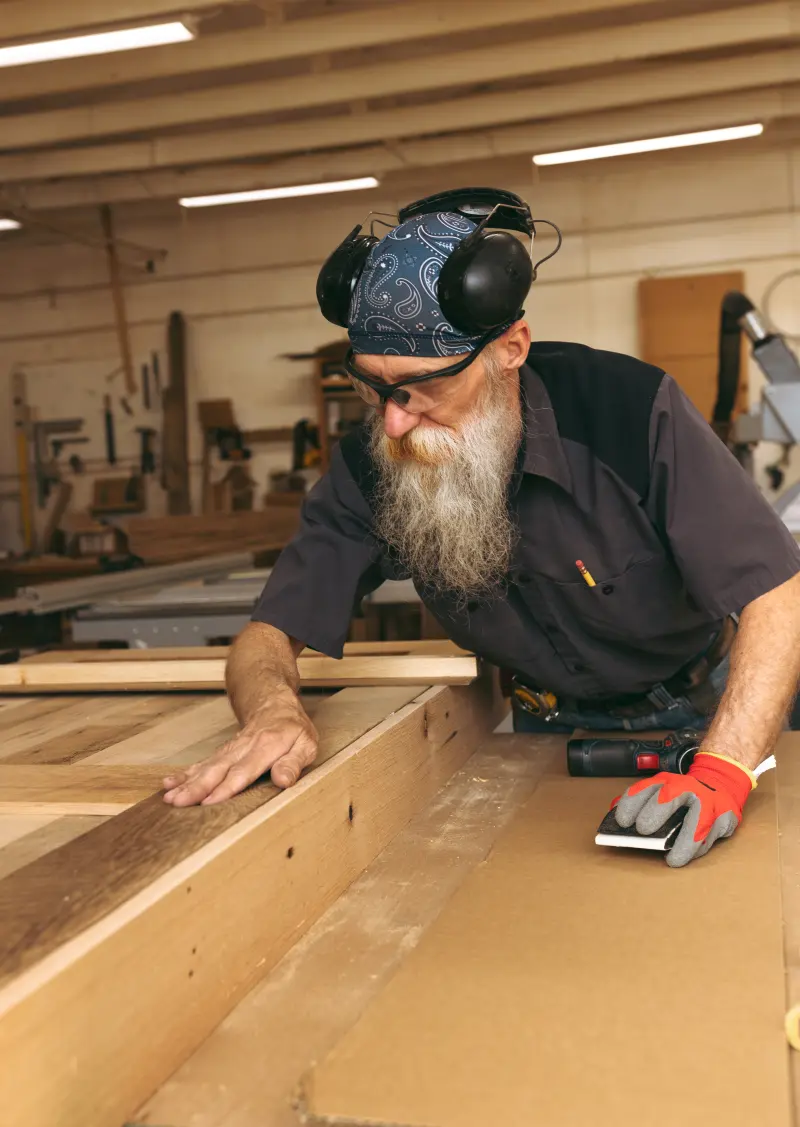 Troy hand-sanding reclaimed wood inside our Virginia woodshop.