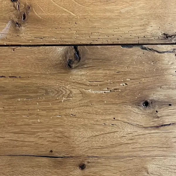 Close-up of a sound, dark knot and a natural void in a beam-sawn oak plank, showcasing the old-growth grain pattern.