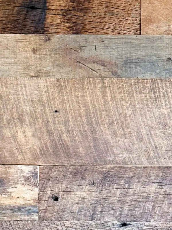 A group of several Brown Board reclaimed barnwood planks displayed side-by-side. The image illustrates the beautiful range of deep chocolate to warm tan patinas, varied width options, and authentic original face textures found in this unique collection.