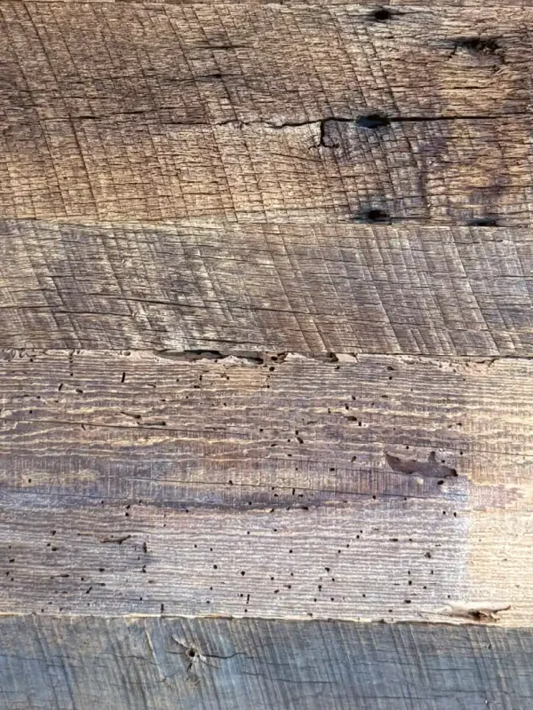 Detailed view of genuine antique barn wood wall boards showcasing original 19th-century milling marks, natural checking, and a deep, stable brown patina forged over a century of service.