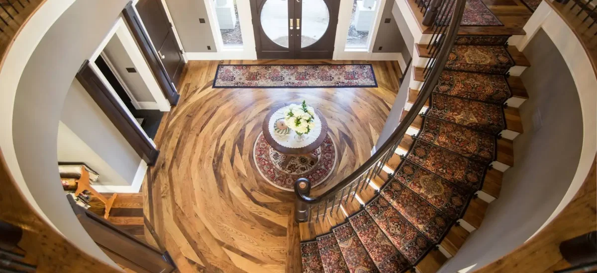 Reclaimed wormy chestnut flooring in a luxury grand foyer featuring a custom concentric circular installation pattern.