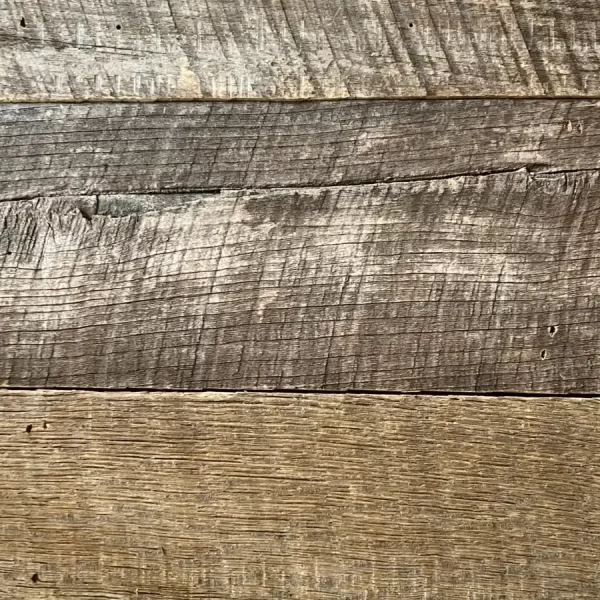 Natural aging stress cracks and stable checking in century-old reclaimed barnwood wall cladding.