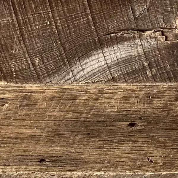 Historic fastener marks and blackened iron nail shadows on reclaimed barnwood wall boards.