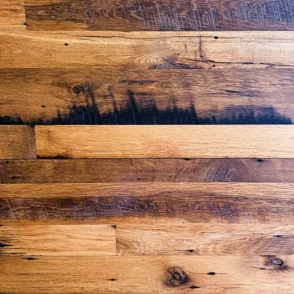Reclaimed oak flooring showcasing the texture and character of the wood, with visible saw marks, knots, and natural variations.