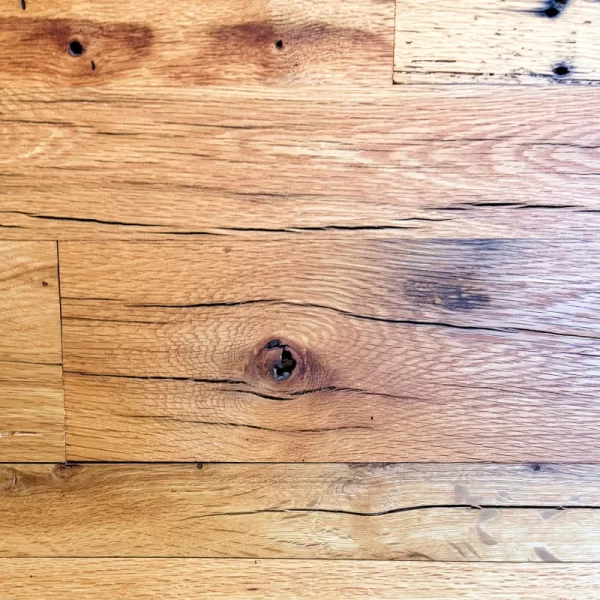 Reclaimed barn board oak flooring displaying aging stress cracks, a natural characteristic also referred to as checking.