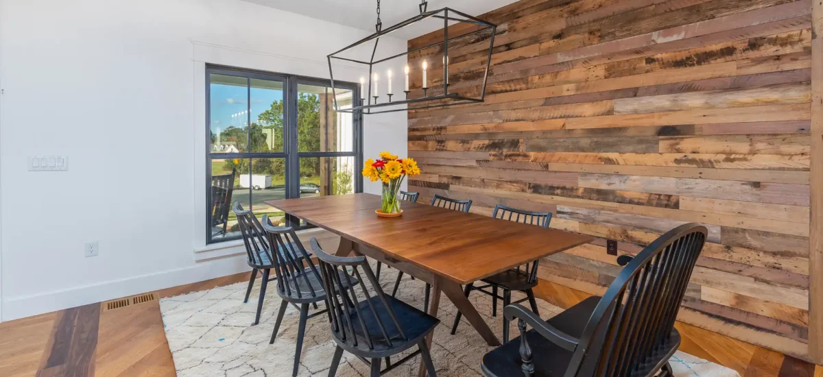 Reclaimed mixed-tone wood cladding serving as a focal wall behind a modern farmhouse dining table.
