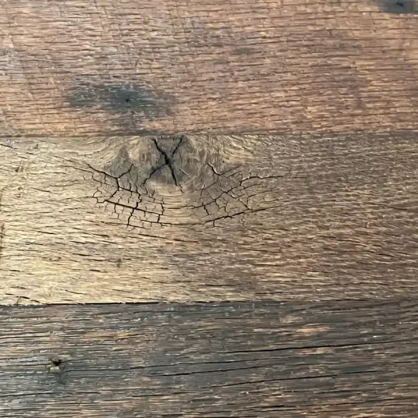 Textured salvaged oak floor planks revealing historic checking and rich patina from century-old weathering.